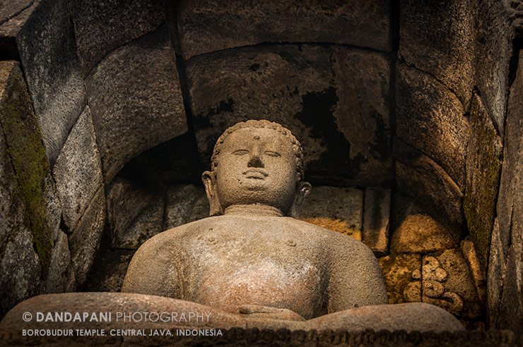 A large statue of a meditating Buddha graces one of the perimeter walls of the temple