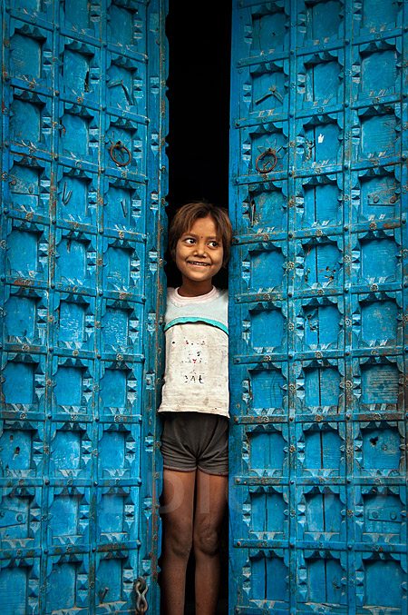 Indian girl standing next to colorful door