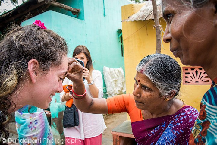 The village ladies place a pottu or bindu on the forehead of our travelers.